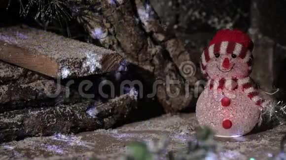 一个戴着红帽子的雪人戴着闪烁着灯光的木屋背景视频的预览图
