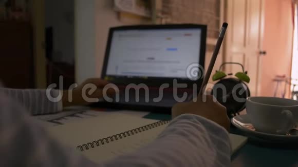 女商人用笔记本电脑在桌子上工作女人的手在记事本上写字在家里喝一杯咖啡视频的预览图
