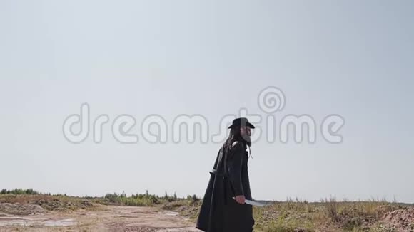 一个留胡子的人穿着黑色斗篷在沙漠里找人视频的预览图