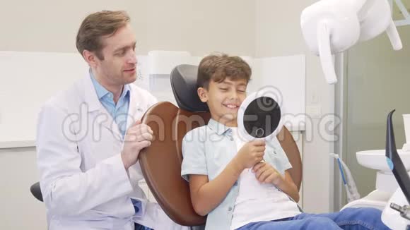 可爱的男孩在牙齿检查后在镜子里检查他健康的牙齿视频的预览图