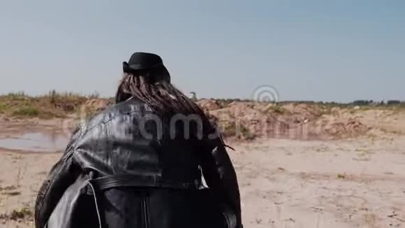 一个穿着黑色外套和帽子的人手里拿着一把刀穿过沙漠视频的预览图