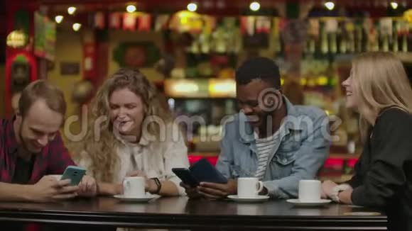 漂亮的西班牙裔男人在她的智能手机上向她的朋友展示有趣的东西而他们在酒吧玩得很开心他们视频的预览图