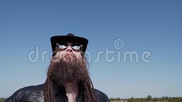 一个穿着黑色斗篷帽子胡须和眼镜的人站在沙漠里看着天空视频的预览图