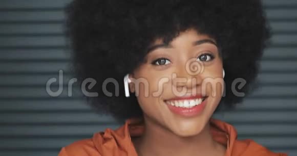年轻快乐的非洲裔美国妇女戴着耳机听音乐和在镜头中跳舞的肖像视频的预览图