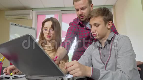 成熟的男教师帮助学生完成作业使用笔记本电脑视频的预览图