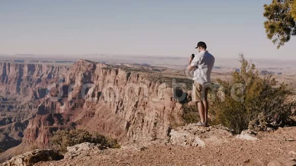 快乐的年轻游客拍智能手机照片史诗般的夏季风景站在令人难以置信的大峡谷美国视频的预览图