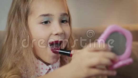 小小的漂亮的女孩涂口红化妆很有趣视频的预览图