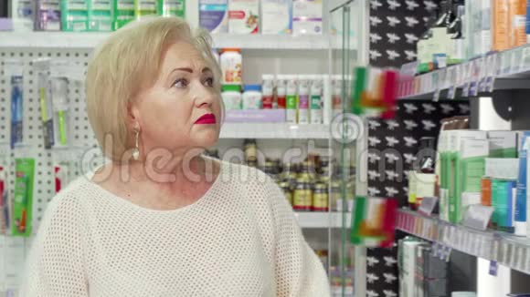 迷人的老妇人对着镜头微笑在药店购物视频的预览图