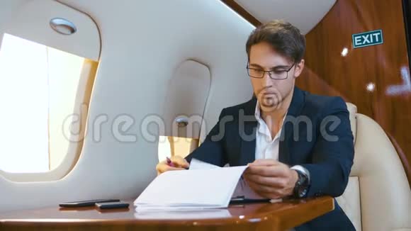 忙碌的商人在私人飞机上飞行时处理文件商务舱视频的预览图