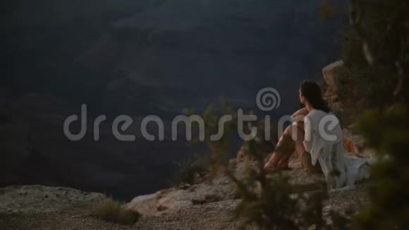 慢动作美丽的年轻女子头发随风飘扬坐在令人难以置信的夏日日落美景大峡谷视频的预览图