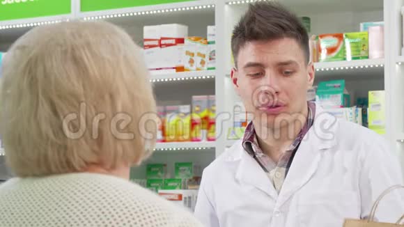 英俊的年轻药剂师把购物袋交给顾客视频的预览图