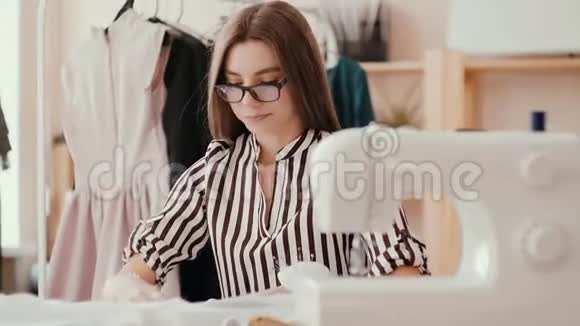 裁缝女孩用手抚平桌子上的布料用铅笔做记号在前景是视频的预览图