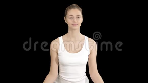 年轻女子坐在莲花的姿势闭着眼睛冥想阿尔法通道视频的预览图