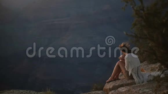 慢动作和平的年轻女子与飞毛坐在史诗般的日落山全景在雄伟的大峡谷视频的预览图