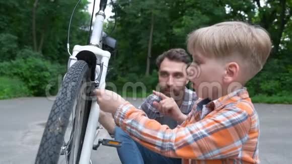 小男孩和他父亲修理自行车的肖像视频的预览图