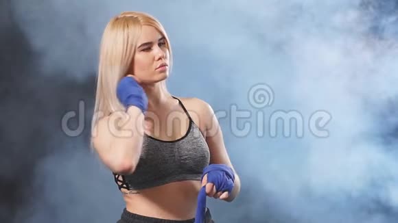 年轻的白种人集中女运动员用蓝色弹性绷带包裹他的拳头慢动作视频的预览图