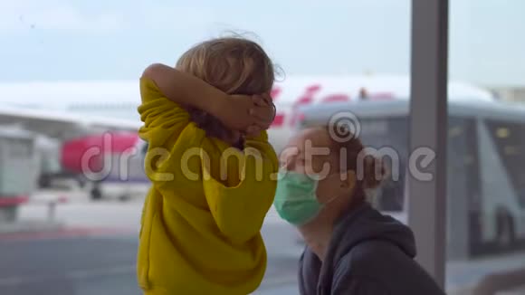 小男孩和他的母亲戴着医用口罩在机场等候他们的航班视频的预览图