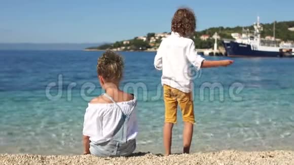 后景卷曲的男孩和女孩在地中海海岸玩鹅卵石克罗地亚亚得里亚视频的预览图