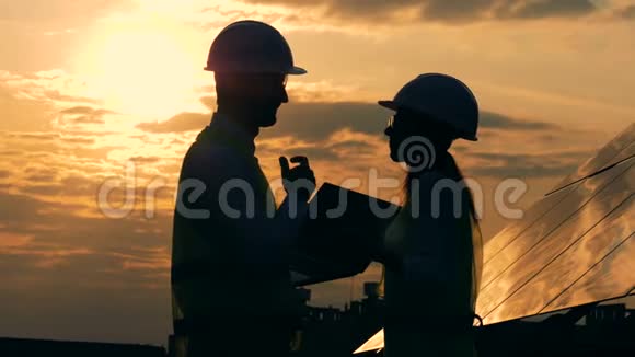 男女建筑工人谈一谈夕阳背景侧观视频的预览图