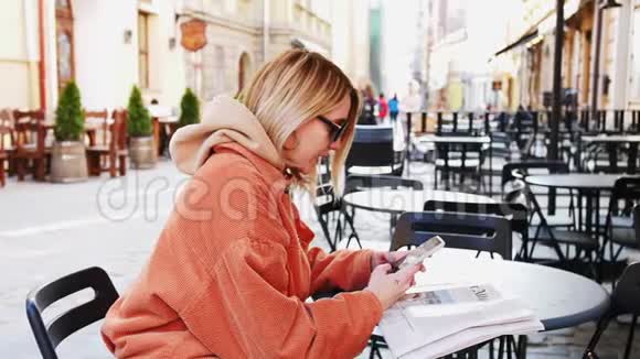 美丽的年轻女商人穿着白色衬衫在城市里散步时使用现代智能手机视频的预览图