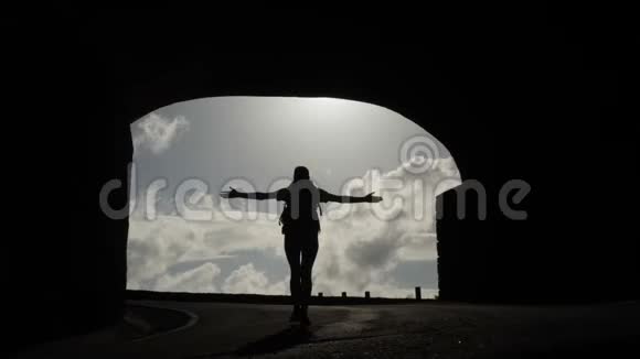 镜头跟随一个女人的剪影从隧道向阳光走去明亮的光爆发举起武器视频的预览图
