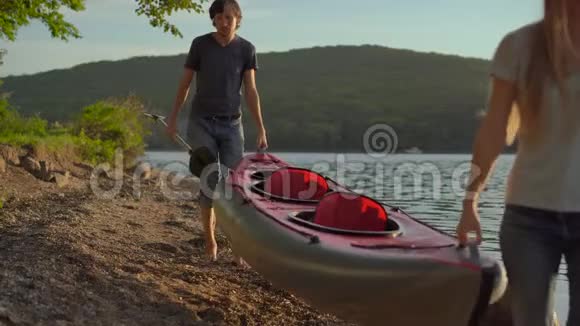 一群年轻的男女游客在海边或湖边载着一艘充气大皮艇视频的预览图