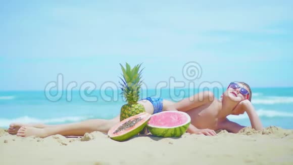 男孩躺在海滩上背着大海的异国水果组成视频的预览图