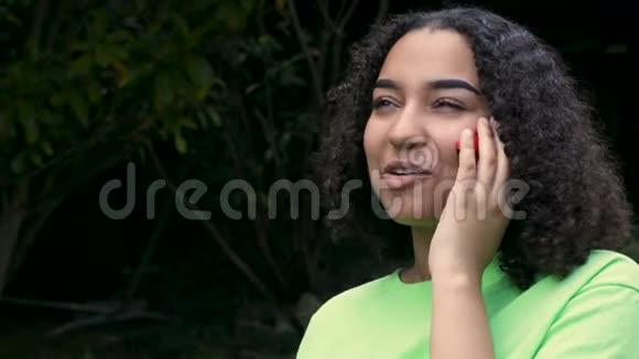 一位美丽的混血非洲裔美国少女少女正在用手机或智能手机打电话视频的预览图