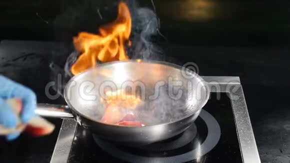 食品视频概念厨师戴着蓝色手套在餐厅厨房煮火焰菜把切好的桃子放在火里视频的预览图