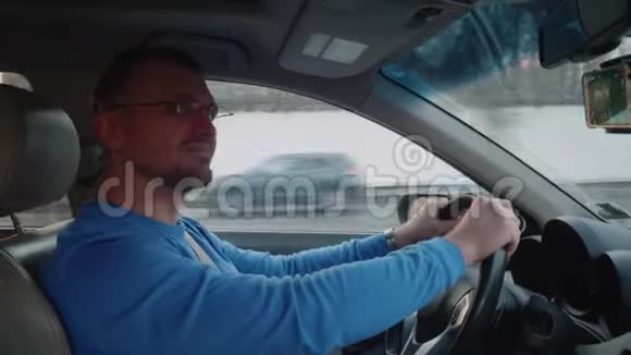 白色司机在车上看着右后视镜微笑日落的天空冬天晴朗的一天视频的预览图