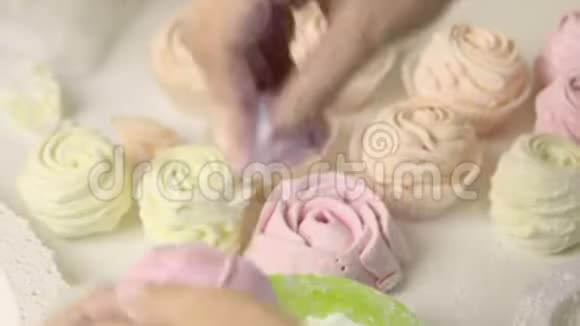 一个女人在糖霜中以玫瑰的形式卷棉花糖桌子表面附近有现成的棉花糖视频的预览图