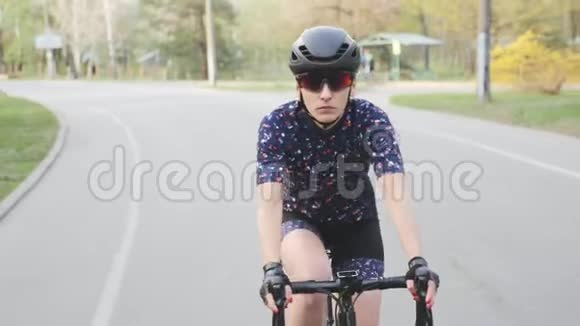 在公园里骑自行车的女自行车前景戴着黑色头盔和眼镜视频的预览图