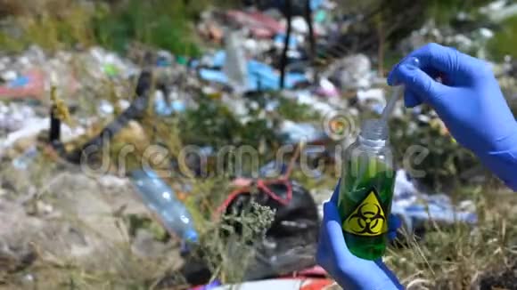 从装有生物危险标志的瓶子中取出样品并在垃圾填埋场上交手套视频的预览图