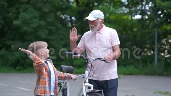快乐爷爷教男孩如何在夏天公园骑自行车家庭世代安全和人的概念视频的预览图