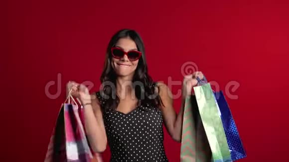 快乐的年轻女子购物后用五颜六色的纸袋隔离在红色上视频的预览图