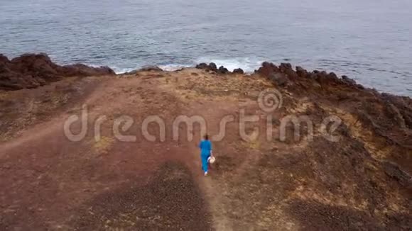 在一个保护区内一位穿着漂亮蓝色连衣裙的女士漫步到山顶视频的预览图