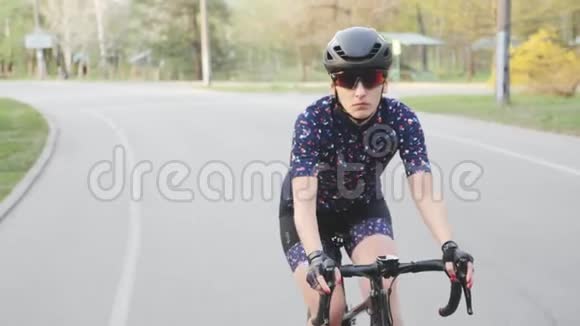 在公园里骑自行车的女自行车前景戴着黑色头盔和眼镜慢动作视频的预览图