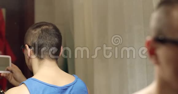 一个人手里拿着一面小镜子把头上的头发剃了视频的预览图