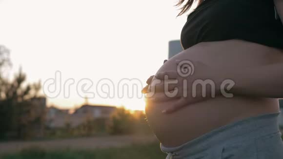 在日落时分孕妇在户外踩着她的胃视频的预览图