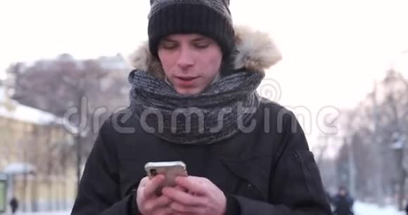 冬天寒冷的一天男人走路和使用手机视频的预览图