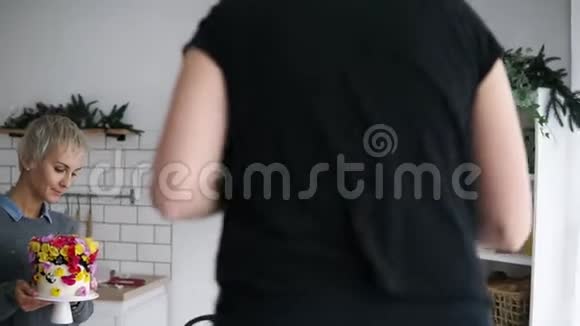 女性糖果师在她的厨房里用鲜花蛋糕装饰拍照的过程蛋糕的目标焦点视频的预览图