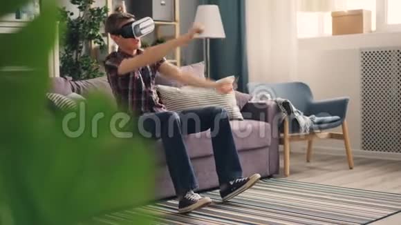 兴奋的家伙正在玩增强现实眼镜戴着耳机玩赛车游戏移动手和腿视频的预览图