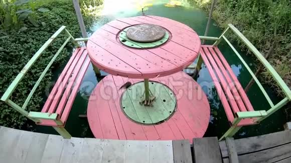 一张用旧电缆做成的木桌在荷塘旁边伞展开了视频的预览图