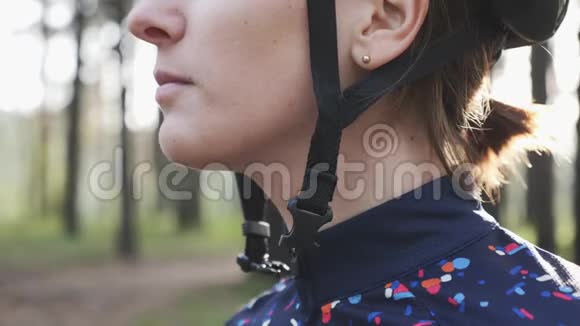 在铁人三项比赛前有注意力的骑自行车的女人戴上头盔和夹子铁人三项的概念慢动作视频的预览图