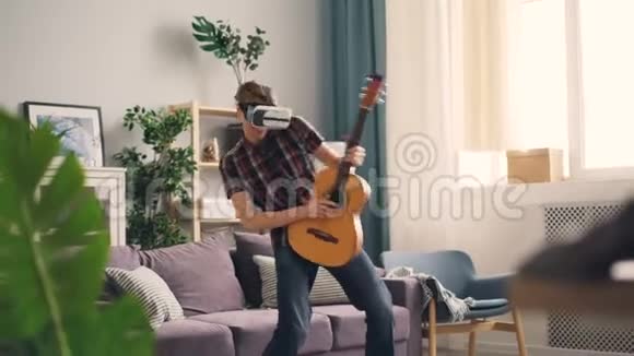 有趣的青少年正在玩虚拟现实眼镜戴着耳机拿着吉他和移动的身体仿佛视频的预览图