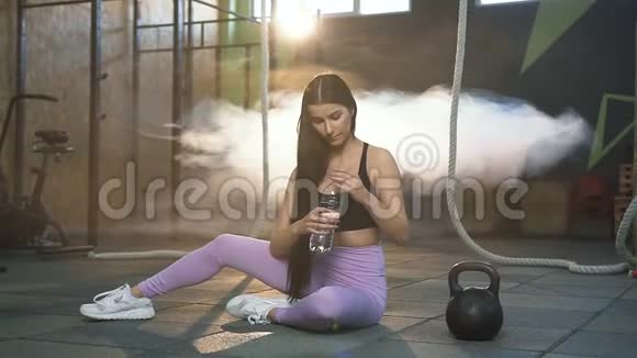 漂亮的适合女性在健身房训练后休息时喝水视频的预览图