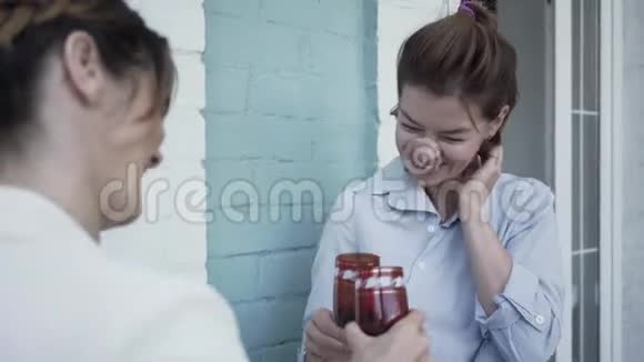 两个女朋友站在阳台上放松喝酒可爱的成熟女人在家里在一起视频的预览图