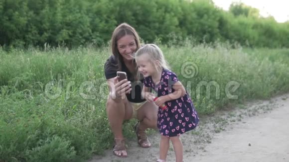 漂亮的年轻妈妈和女儿在电话里自拍视频的预览图