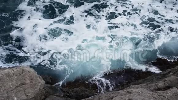 海浪拍打着海泡沫的俯视图潮汐袭来的湿崖视频的预览图