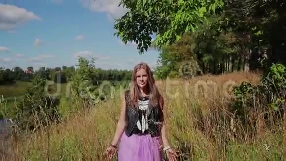 一个漂亮的女孩走在高高的河岸上穿过高高的草地看着一边走进镜头视频的预览图